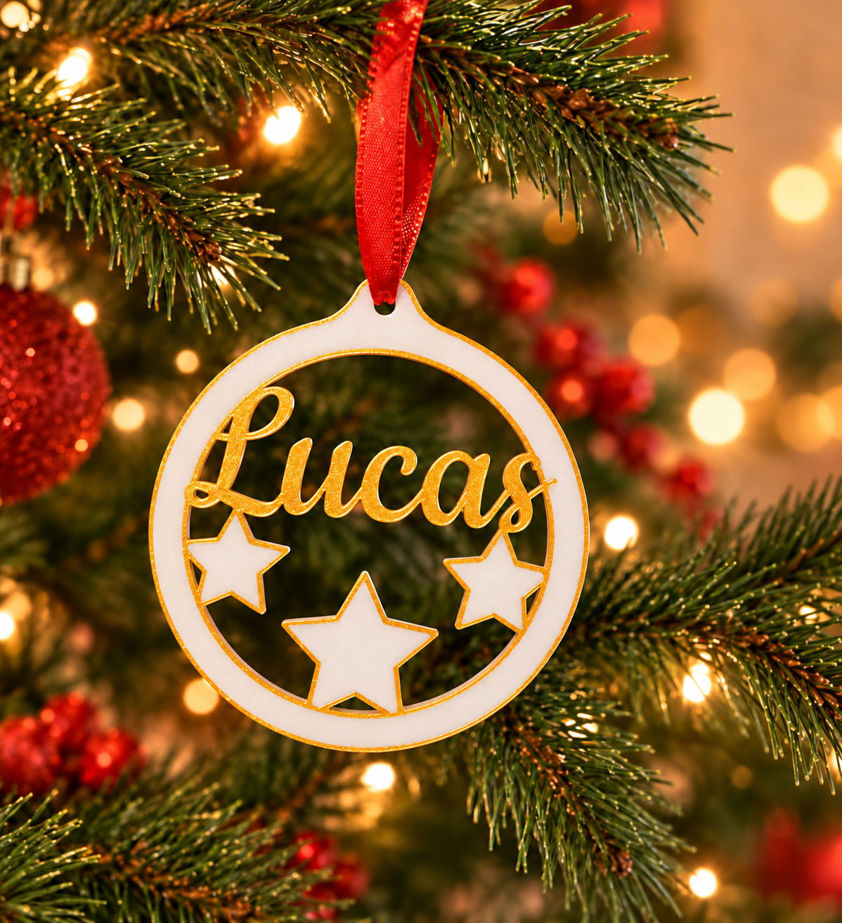 Bola navideña personalizada de tres estrellas con nombre Lucas, blanca y dorada, colgada en un árbol de Navidad